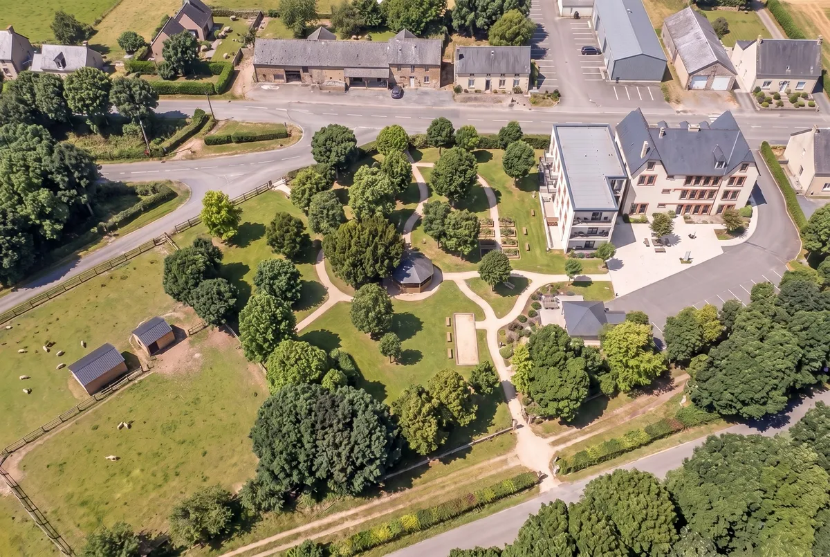 Vue aérienne de la résidence et de son parc : le potager, le kiosque, le terrain de pétanque, la cuisine d'été et la petite ferme, la voie verte en lisière des bois.